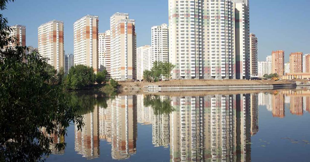 MHF und Immobilien mit Eigentumswohnungen in Ufernähe. Die Häuser spiegeln sich im Wasser.